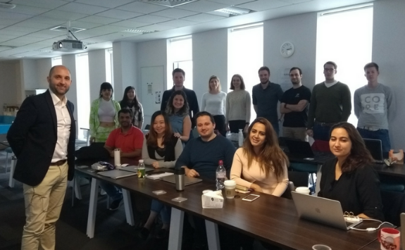The Founder of Boilerplan and the MBA cohort smile at the camera in the MBA classroom